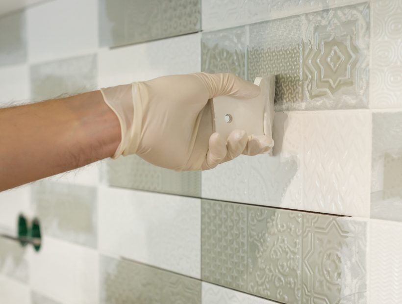 Closeup of tiler hand rubbing tile, Installing and grouting decorative finishes Closeup of tiler hand rubbing tile, Installing and grouting decorative finishes